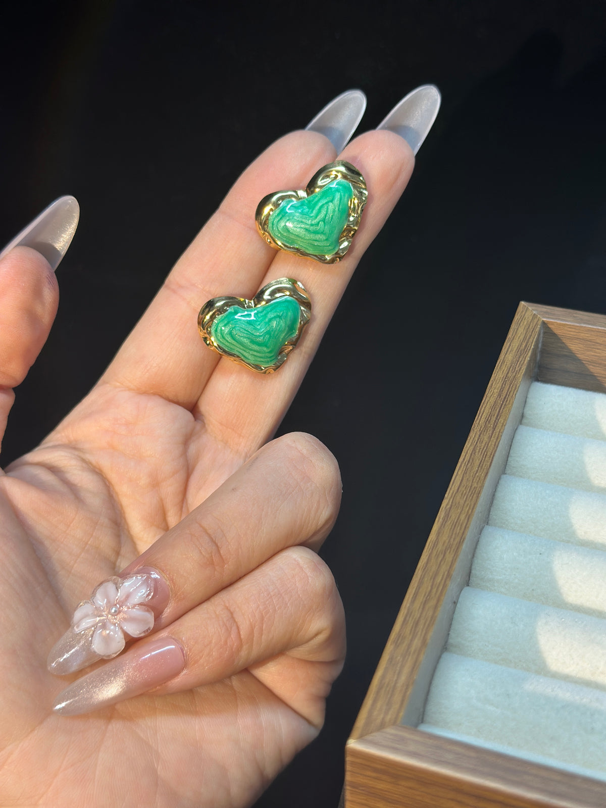 Green sculptural heart stud earrings with flowing textured green centres and polished gold-tone borders