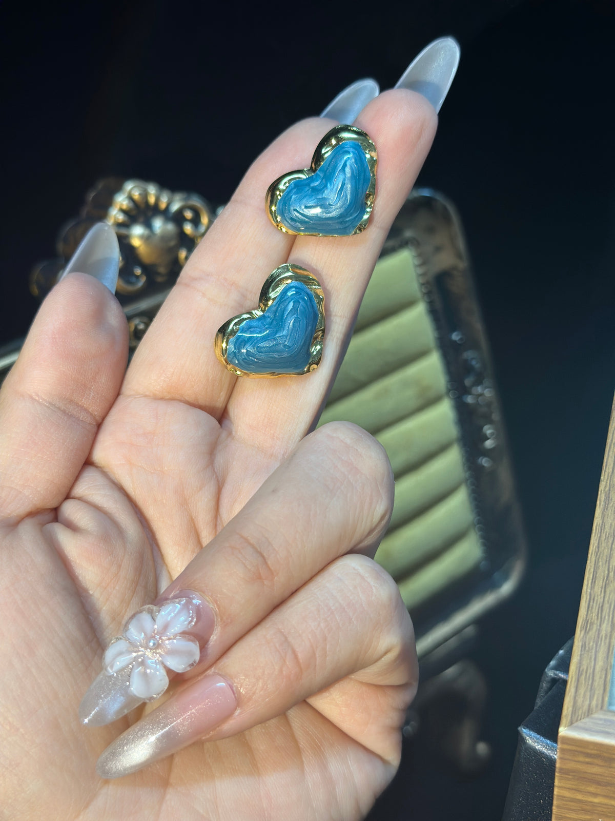 Blue sculptural heart stud earrings with flowing textured blue centres and polished gold-tone borders