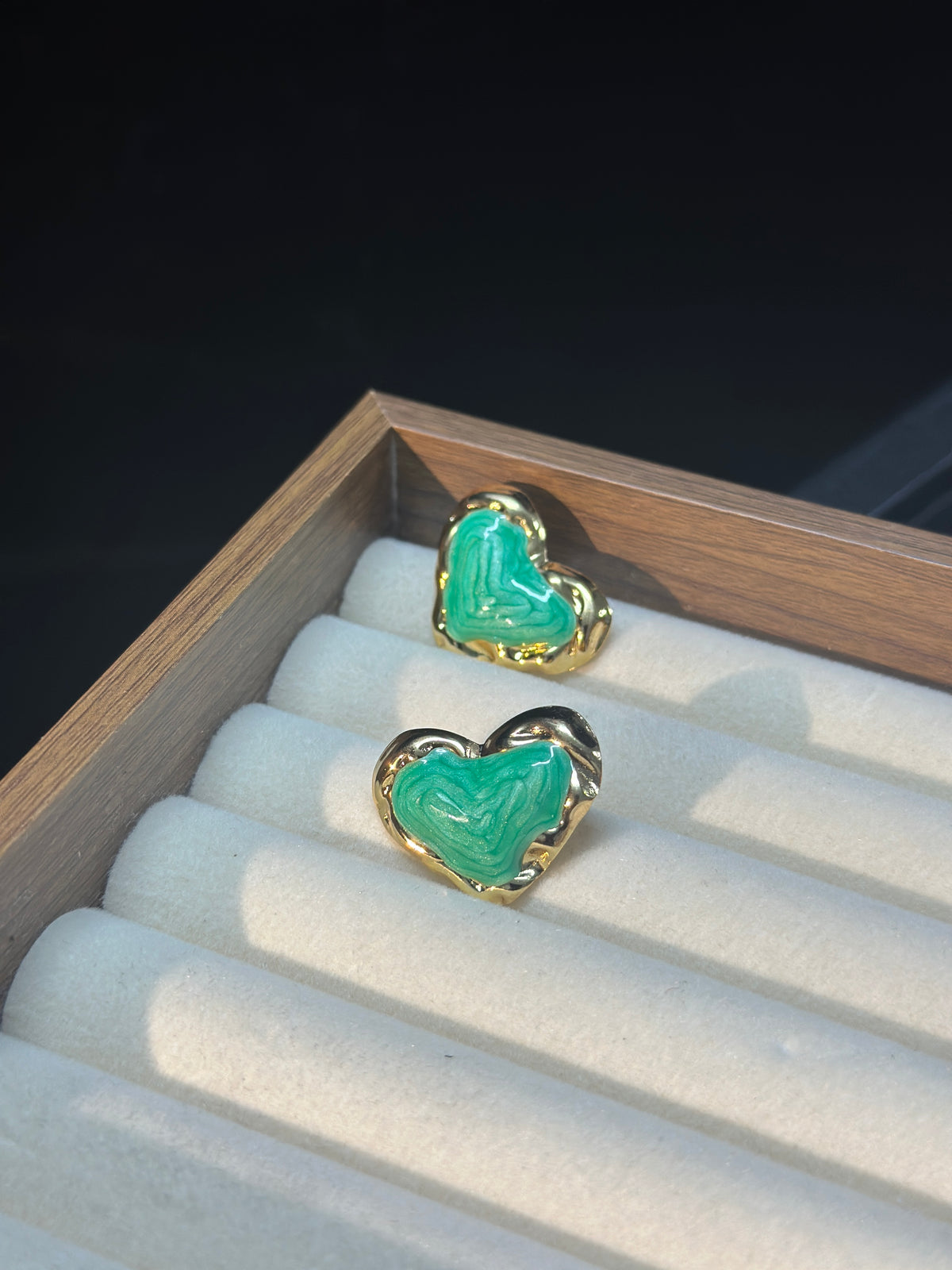 Green sculptural heart stud earrings with flowing textured green centres and polished gold-tone borders