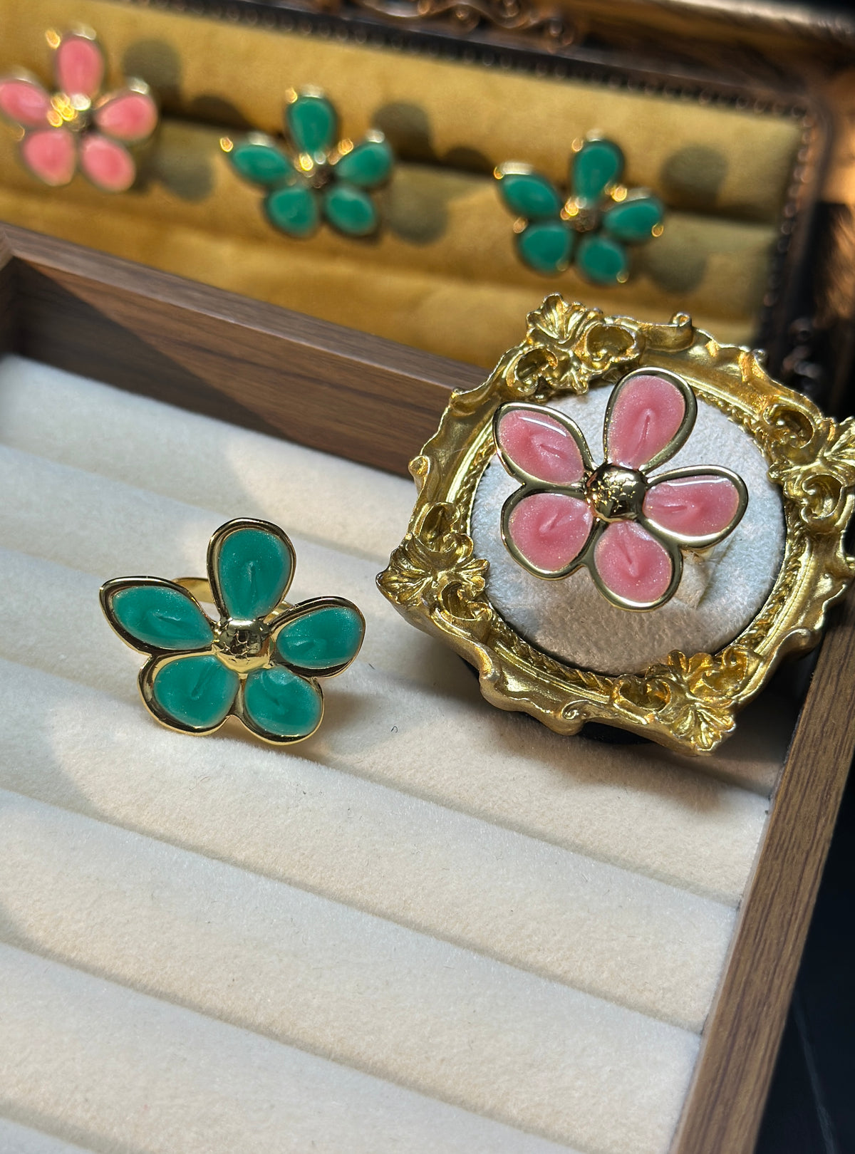 Set of two adjustable five-petal flower rings in pink and teal green with gold-tone details