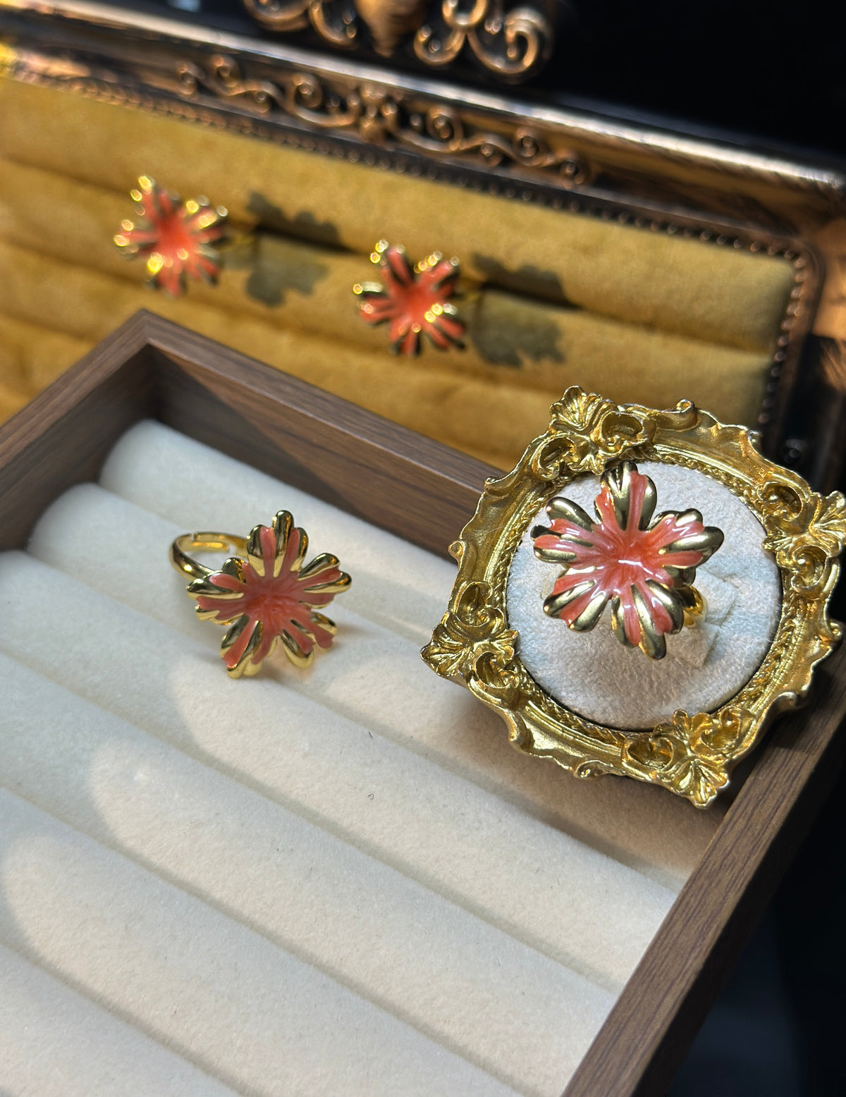 Coral pink sunburst flower adjustable ring with glossy petals, raised swirl detailing and gold-tone outlines