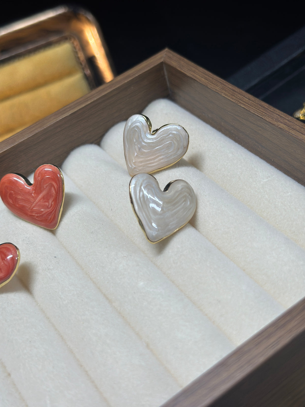 Pearl white heart stud earrings with a luminous pearlescent finish, subtle flowing textures and delicate gold-tone edges