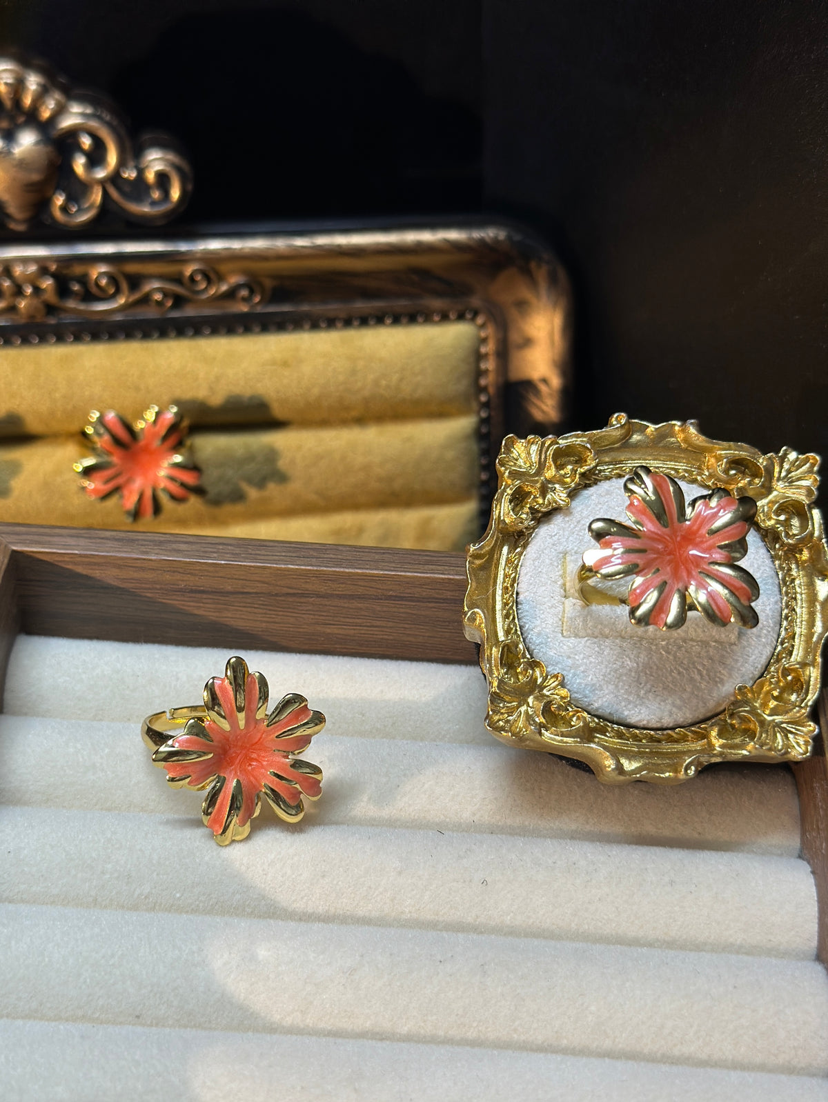 Coral pink sunburst flower adjustable ring with glossy petals, raised swirl detailing and gold-tone outlines