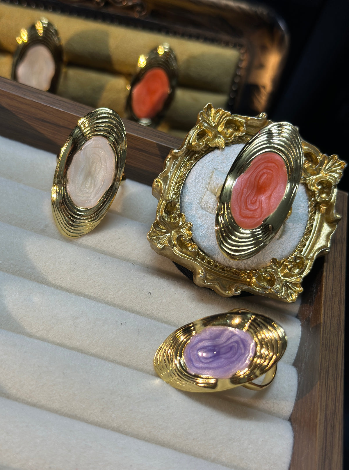 Coral pink oval swirl adjustable ring with raised centre detailing and layered gold-tone frame
