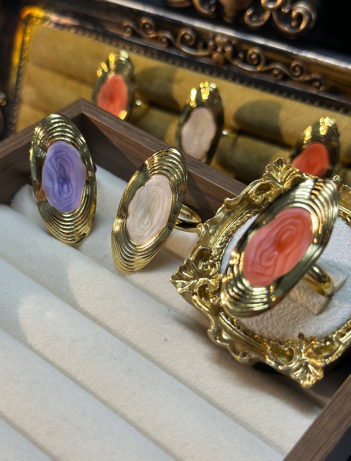 Coral pink oval swirl adjustable ring with raised centre detailing and layered gold-tone frame