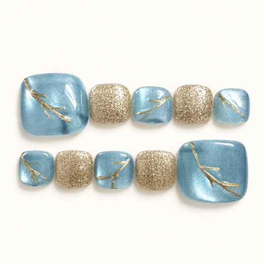 Blue and gold handmade press-on toenails featuring icy blue shimmer, champagne gold glitter and delicate gold branch detailing