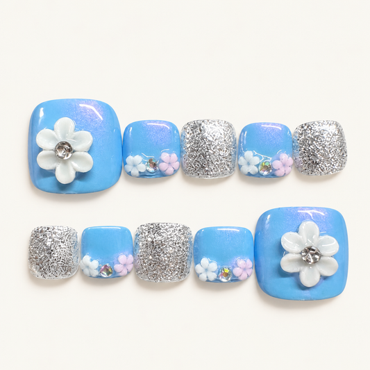 Blue floral handmade press-on toenails with white and pastel pink flowers and silver glitter accents