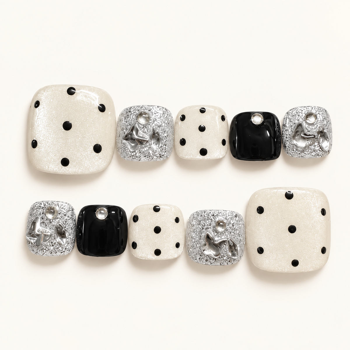 Ivory pearl press-on toenails with black polka dots, glossy black accents, silver glitter and decorative silver bows