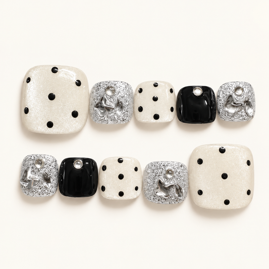Ivory pearl press-on toenails with black polka dots, glossy black accents, silver glitter and decorative silver bows