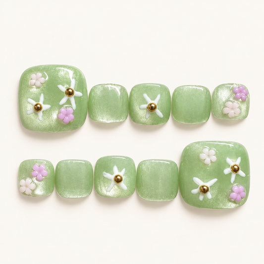3D floral green press-on toenails with pearlescent shimmer, white and pink-purple flowers, and gold accents