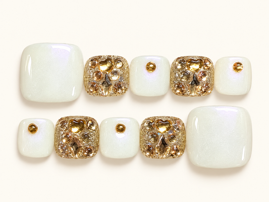 Pearl white press-on toenails with gold embellishments, a glossy finish and subtle pearlescent shimmer