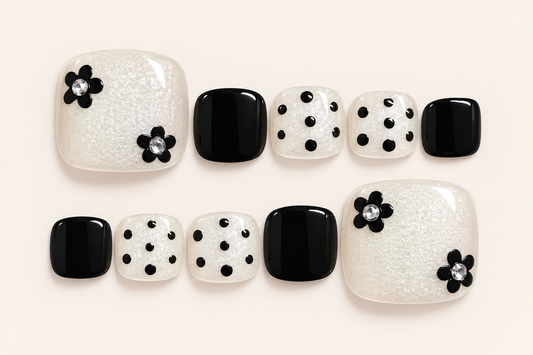 Black and pearl-white press-on toenails with black polka dots, floral decorations and fine shimmer