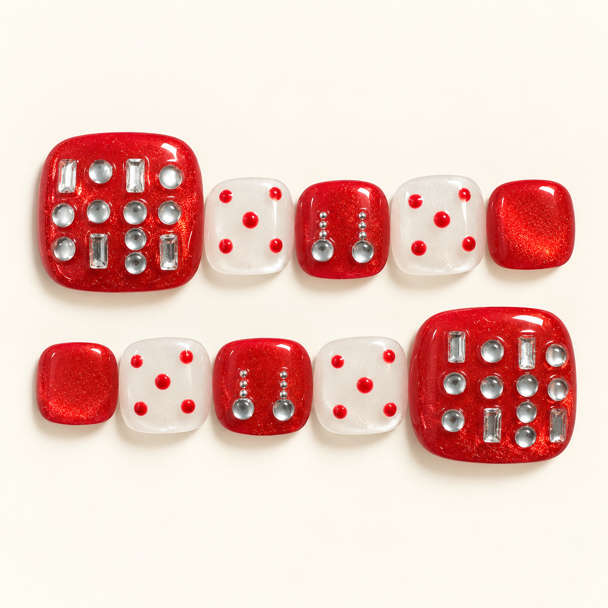 Red shimmer press-on toenails with pearly white red polka dot designs and silver geometric embellishments