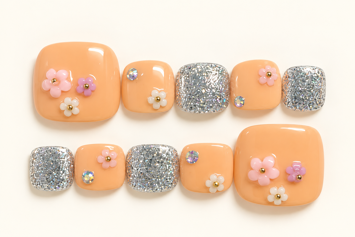 Peach press-on toenails with pink and white floral decorations and sparkling silver glitter accent nails
